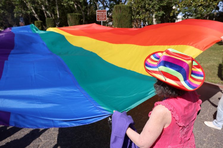 A festivalgoer carries a giant Pride flag during the Sonoma Valley Pride Festival at Sonoma Plaza in Sonoma Sunday, June 1, 2025. (Beth Schlanker / The Press Democrat)