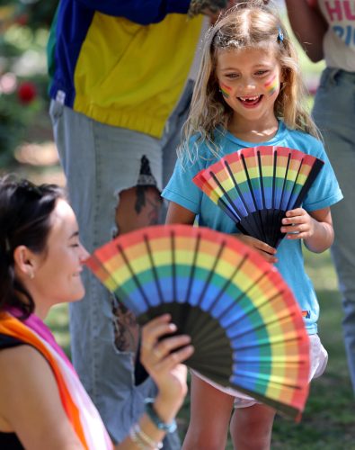 Sutton Beyer, 7, smiles as Bailey Rhude flicks open her fan during the Sonoma Valley Pride Festival at Sonoma Plaza in Sonoma Sunday, June 1, 2025. (Beth Schlanker / The Press Democrat)